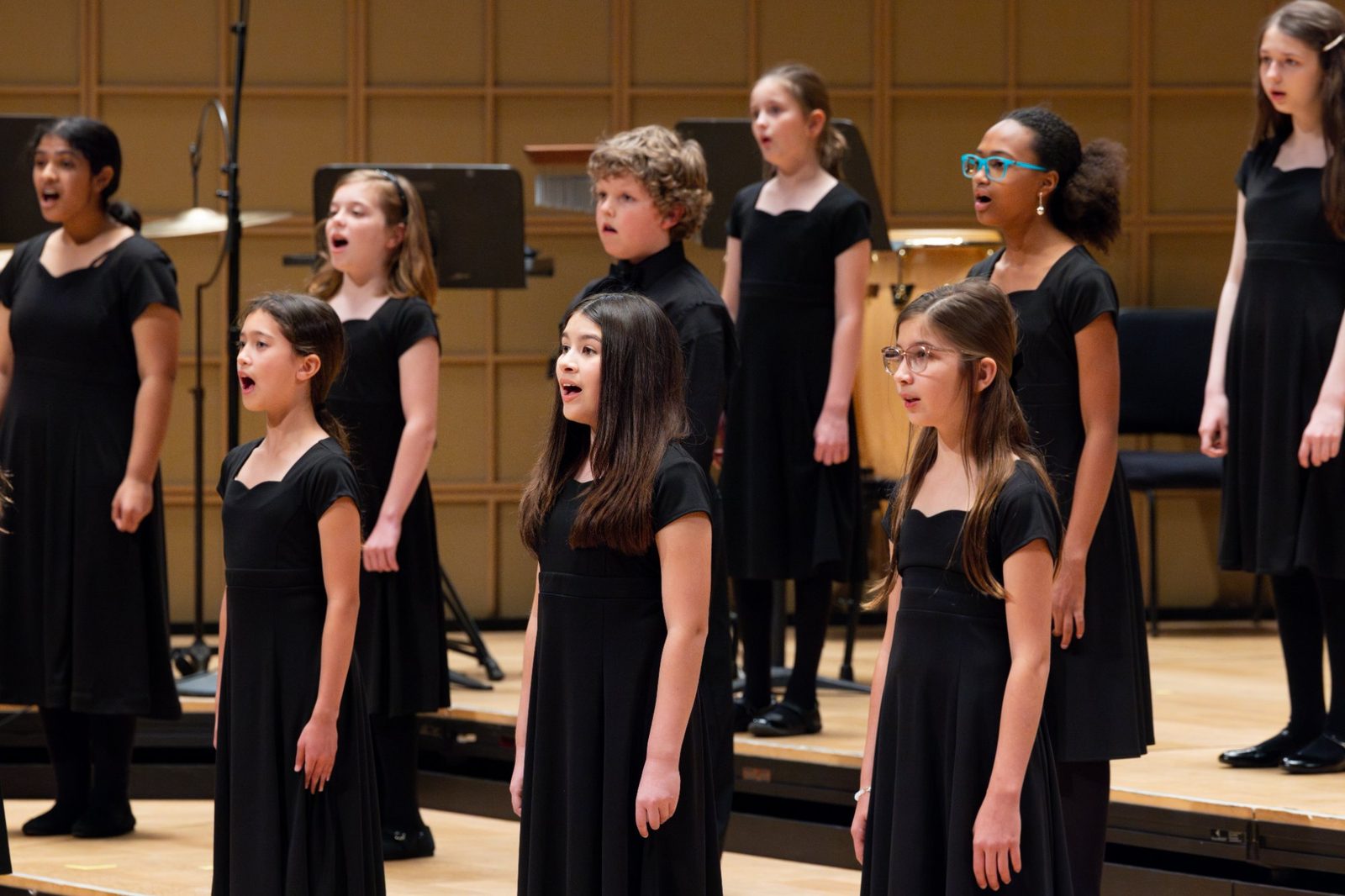 Training Choir choristers in black concert attire singing together on a tiered stage